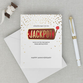 Lifestyle photos with anniversary card featuring a slot machine handle and confetti that reads "everyone says I hit the JACKPOT turns out the real payout keeps getting better" HAPPY ANNIVERSARY