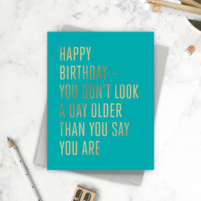 Turquoise birthday card with gold foil text on a marble surface