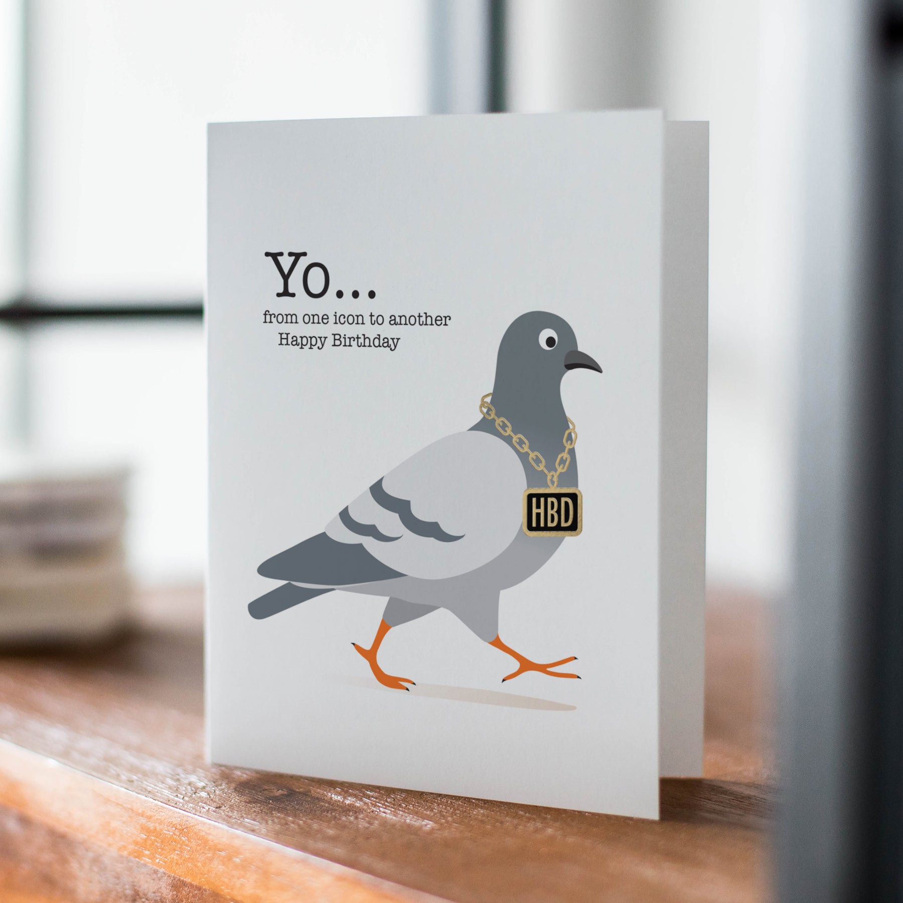 Greeting card with a pigeon illustration and birthday message on a wooden surface.