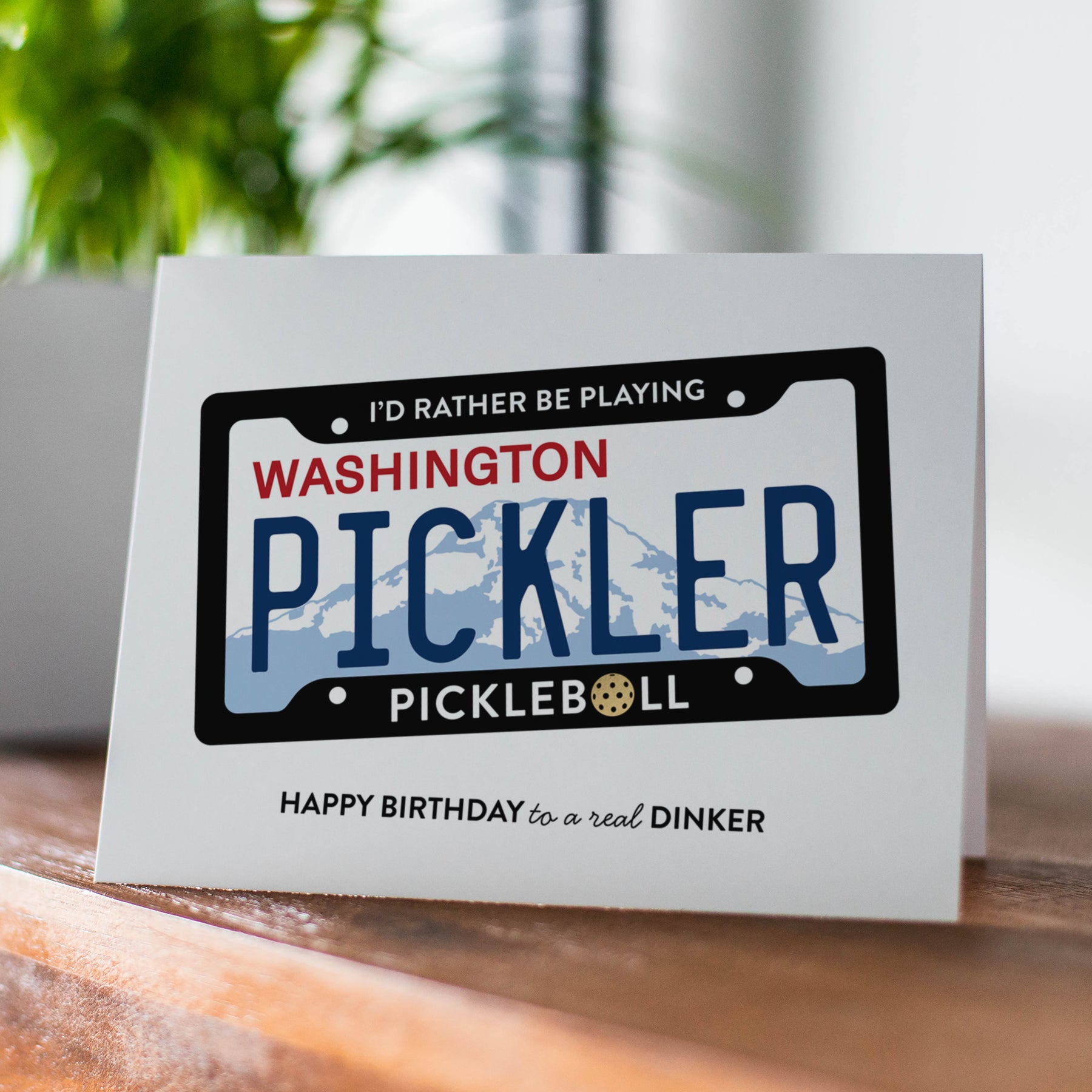 Greeting card with a license plate design and text on a wooden surface.