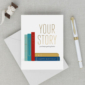 Birthday card with books design and pen on a textured surface