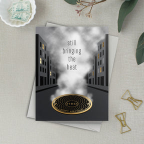 Lifestyle photo of urban themed birthday card that reads "still bringing the heat – Happy Birthday"