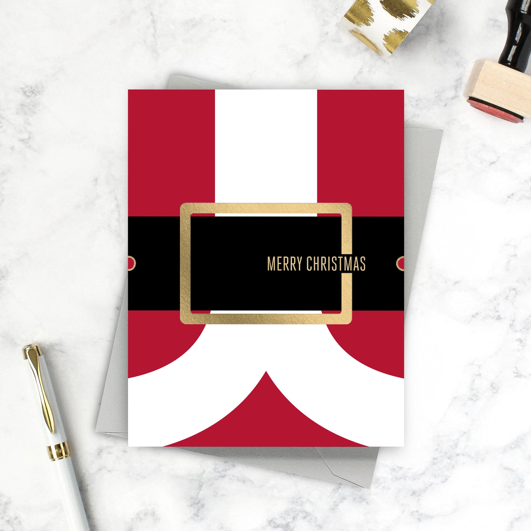 Red and white Christmas card with gold frame and 'Merry Christmas' text on a marble surface.