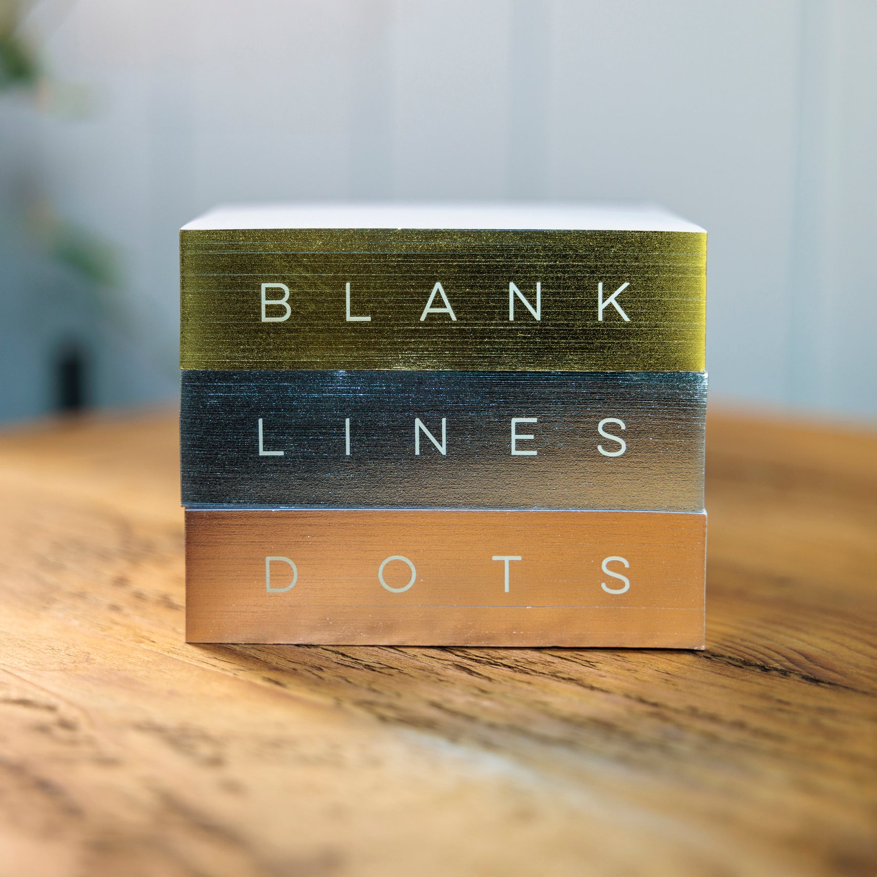 Stack of three notepads with 'Blank, Lines, and Dots' text on a wooden surface